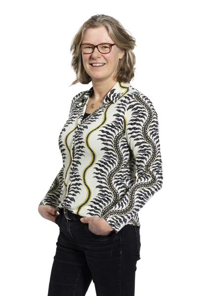 Teamlid Jacqueline in een wit shirt met een zwart-gouden patroon, glimlachend met een ontspannen houding en handen in de zakken. Teamlid Jacqueline in een wit shirt met een zwart-gouden patroon, glimlachend met een ontspannen houding en handen in de zakken.